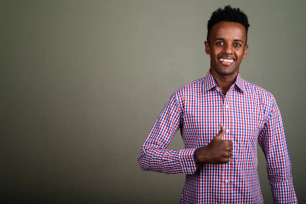 Jonge knappe Afrikaanse zakenman tegen gekleurde achtergrond — Stockfoto