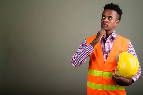 Joven hombre africano guapo trabajador de la construcción contra el color b — Foto de Stock