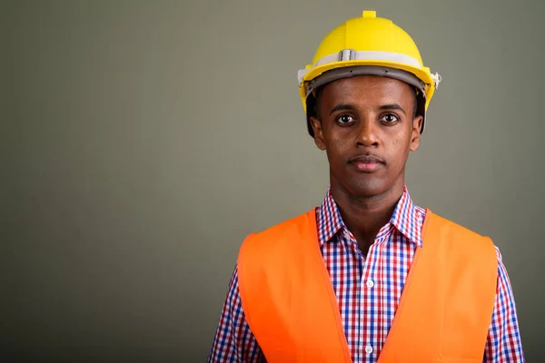 Jovem bonito homem africano trabalhador de construção contra colorido b — Fotografia de Stock