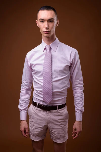 Молодой красивый андрогинный бизнесмен на коричневом фоне — стоковое фото