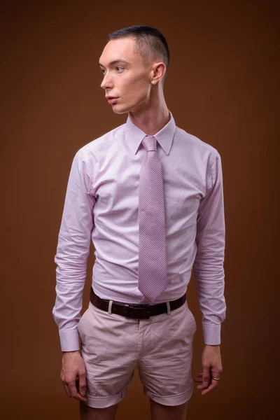 Fiatal jóképű androgün üzletember, barna háttér — Stock Fotó
