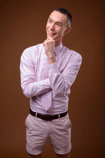 Jonge knappe androgyne zakenman tegen bruine achtergrond — Stockfoto