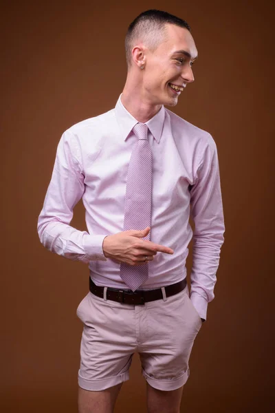 Young handsome androgynous businessman against brown background — Stock Photo, Image