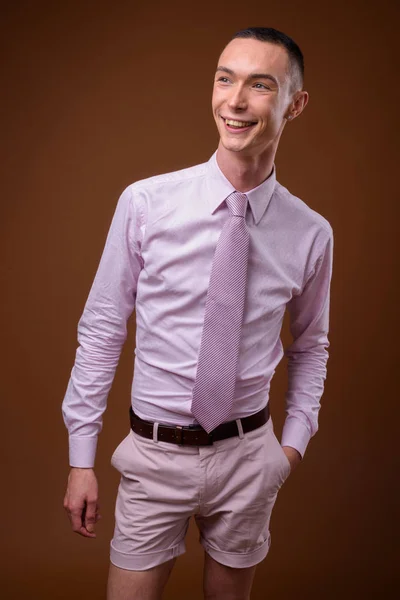 Fiatal jóképű androgün üzletember, barna háttér — Stock Fotó