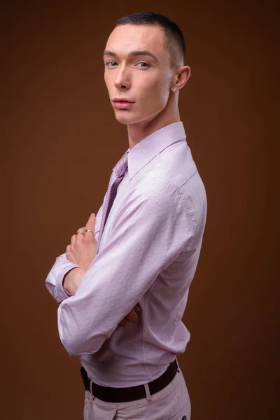 Giovane bello androgino uomo d'affari contro sfondo marrone — Foto Stock
