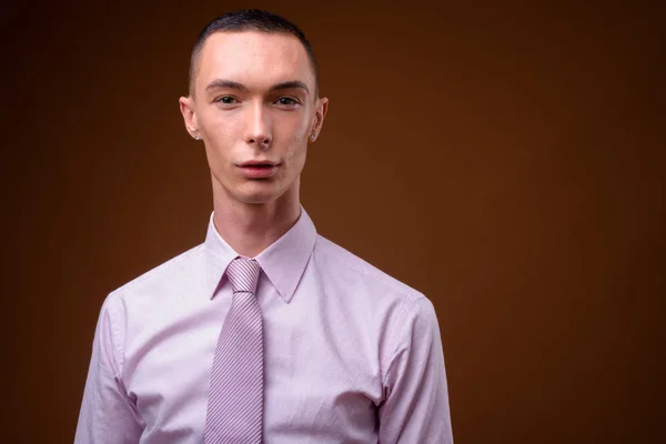 Junger hübscher androgyner Geschäftsmann mit braunem Hintergrund — Stockfoto