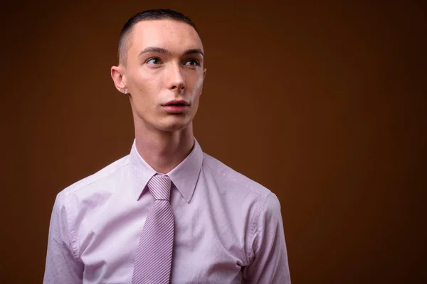 Joven hombre de negocios andrógino guapo sobre fondo marrón —  Fotos de Stock