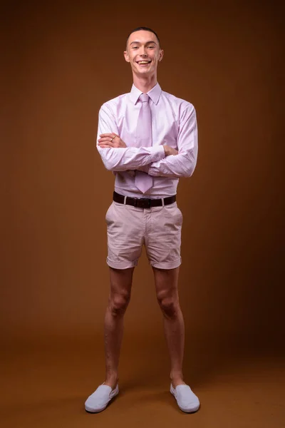 Mladý pohledný hermafroditní podnikatel proti hnědým pozadím — Stock fotografie
