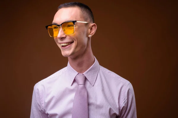 Pemuda tampan androgini pengusaha terhadap latar belakang coklat — Stok Foto