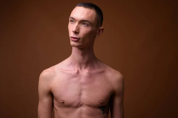 Knappe androgyne jongeman shirtless tegen bruin pagina — Stockfoto