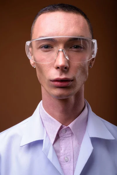 Young handsome androgynous man doctor wearing protective glasses