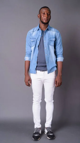 Junger gutaussehender afrikanischer Mann mit kurzen Haaren vor grauem Hintergrund — Stockfoto