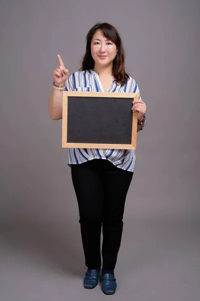 Japanska affärskvinna håller tom blackboard med copyspace — Stockfoto