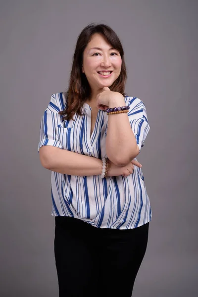 Maturo bella donna d'affari asiatica contro sfondo grigio — Foto Stock