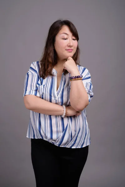 Gammal vacker asiatisk affärskvinna mot grå bakgrund — Stockfoto