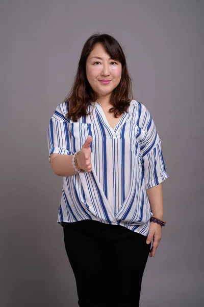 Gammal vacker asiatisk affärskvinna mot grå bakgrund — Stockfoto