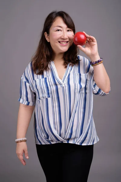 Zralé krásné asijské podnikatelka drží jablko ovoce — Stock fotografie