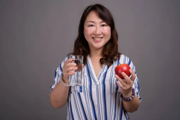 Empresaria asiática sosteniendo vaso de agua y manzana — Foto de Stock