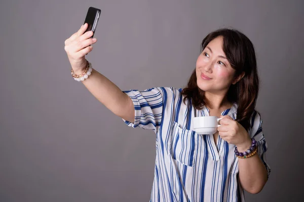 Mature beautiful Asian businesswoman taking selfie with phone — Stock Photo, Image