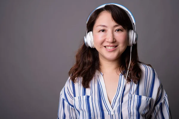 Madura hermosa mujer de negocios asiática escuchando música con auriculares —  Fotos de Stock