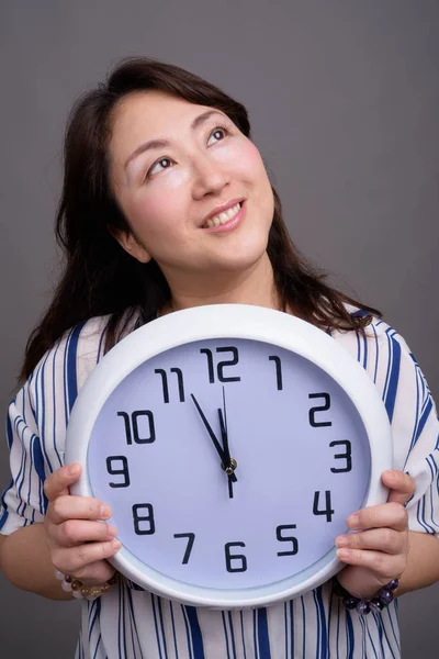 Retrato de madura hermosa mujer de negocios asiática celebración del reloj — Foto de Stock