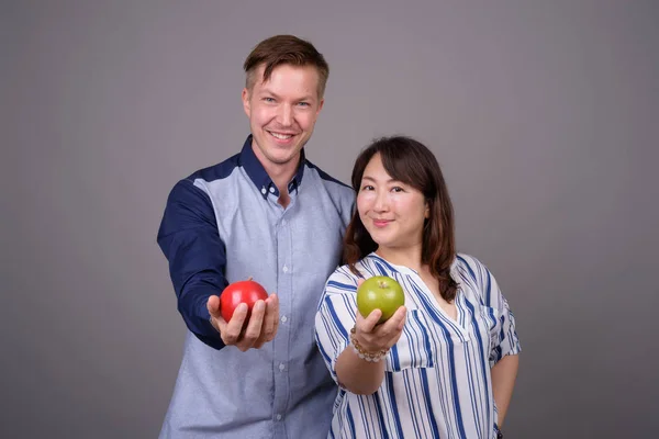 緑と赤のリンゴ果実を保持のスタジオで多民族多様なカップル — ストック写真