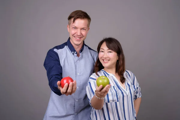 緑と赤のリンゴ果実を保持のスタジオで多民族多様なカップル — ストック写真
