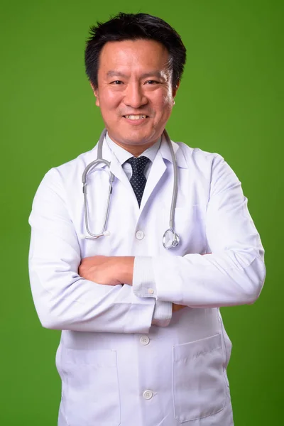 Érett japán férfi orvos ellen zöld háttér — Stock Fotó