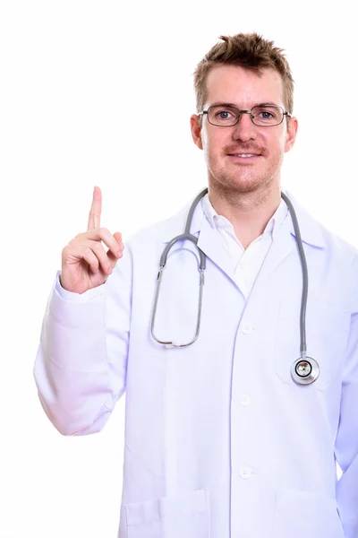 Estúdio tiro de homem feliz médico sorrindo ao apontar o dedo para cima — Fotografia de Stock