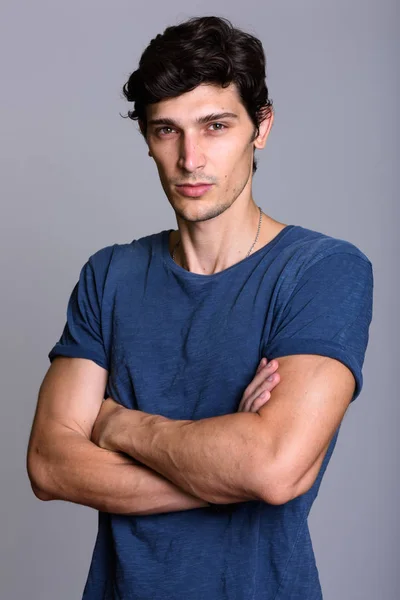 Studio shot of young handsome man with arms crossed — Stock Photo, Image