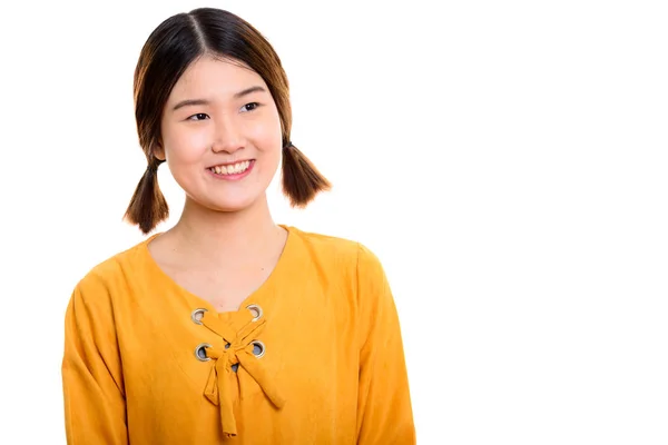 Studio shot van jong gelukkig aziatisch vrouw glimlachen terwijl denken — Stockfoto