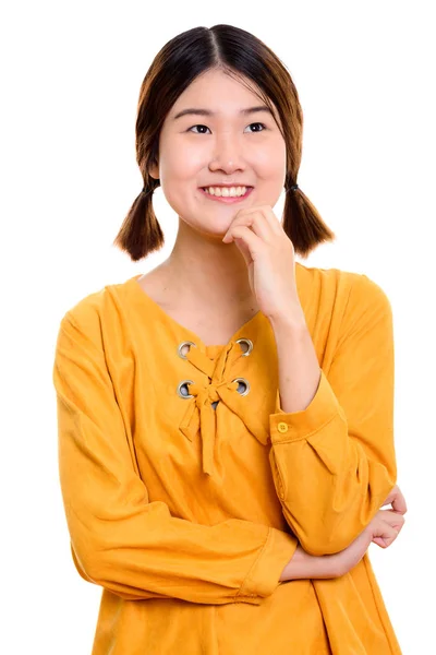 演播室拍摄的年轻快乐的亚洲女人一边想一边笑 — 图库照片