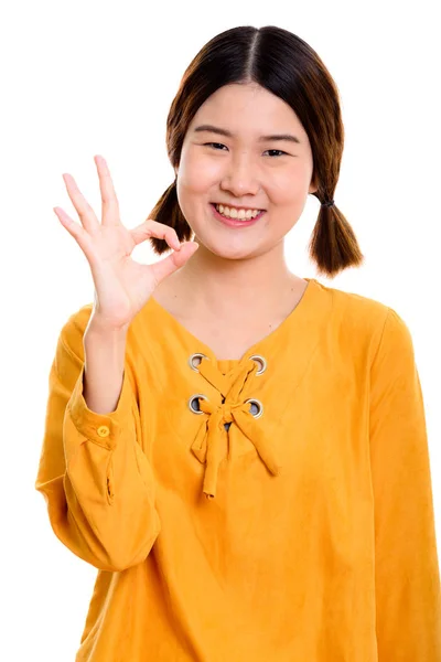 Studio záběr mladá šťastná asijské ženy usmívající se zároveň dává ok s — Stock fotografie