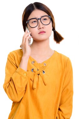 Genç, sıkılmış Asyalı kadın cep telefonuyla konuşuyor.