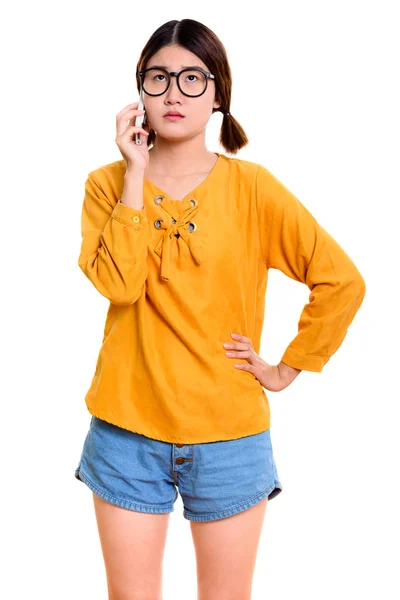 Giovane donna asiatica premurosa in piedi mentre parla sul cellulare ph — Foto Stock