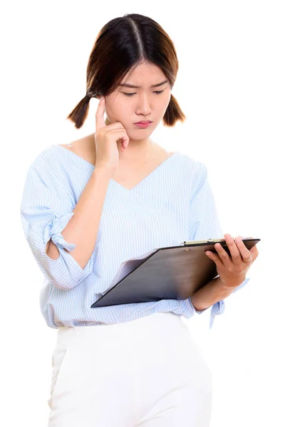 Joven hermosa mujer asiática leyendo en portapapeles mientras piensa — Foto de Stock