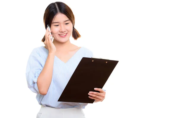 Young happy Asian woman smiling while reading on clipboard and t Stock Photo