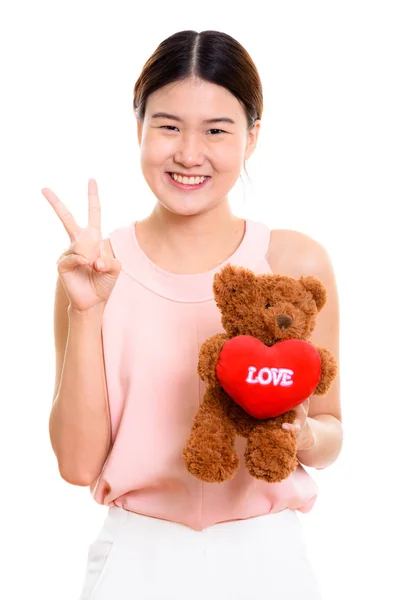 Młoda kobieta azjatyckich szczęśliwy uśmiechający się i trzyma misia z usłyszeć — Zdjęcie stockowe