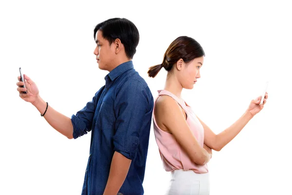 Profile view of young Asian couple using mobile phone together w — Stock Photo, Image