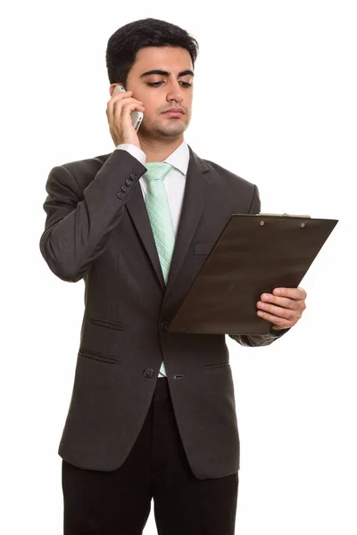 Młody przystojny biznesmen Perski rozmowy na telefon komórkowy, podczas gdy — Zdjęcie stockowe