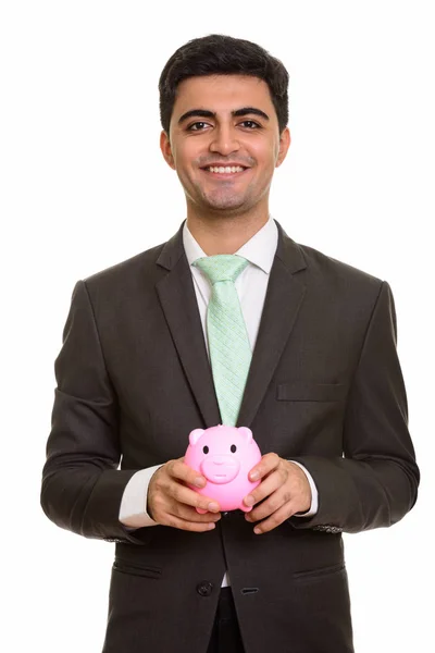Young happy Persian businessman holding piggy bank — Stock Photo, Image