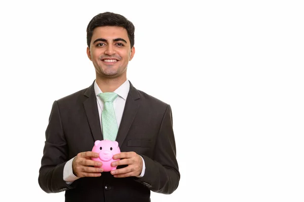Junger glücklicher persischer Geschäftsmann hält Sparschwein — Stockfoto