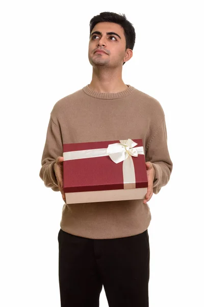 Молодой красивый перс держит подарочную коробку, думая, что готов — стоковое фото