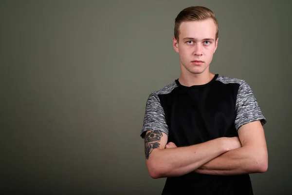 Jovem homem bonito com cabelo loiro contra fundo colorido — Fotografia de Stock