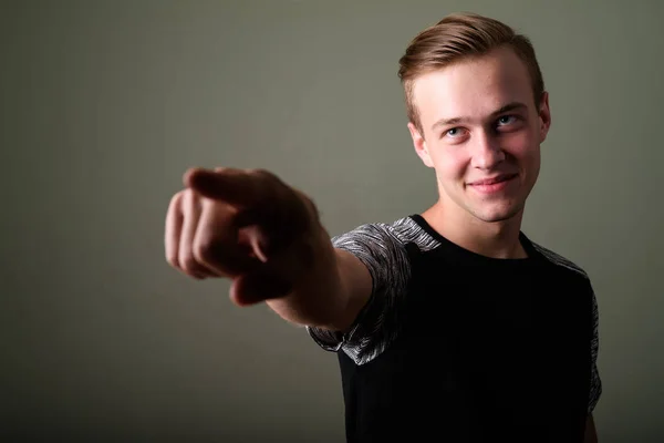 Jeune homme beau aux cheveux blonds sur fond coloré — Photo