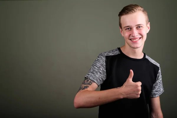 Junger schöner Mann mit blonden Haaren vor farbigem Hintergrund — Stockfoto