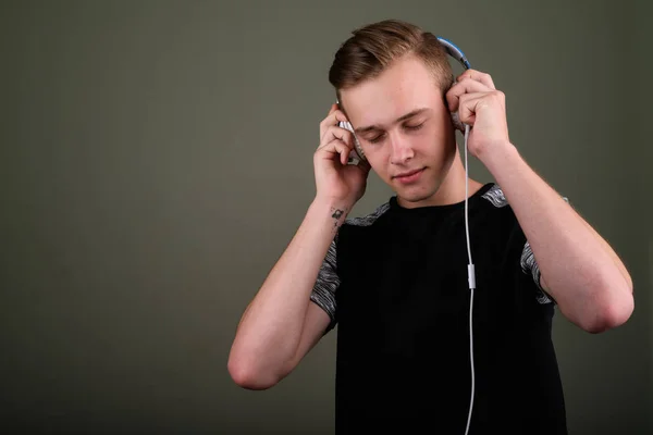 Junger gutaussehender Mann mit blonden Haaren, der Musik gegen Co hört — Stockfoto