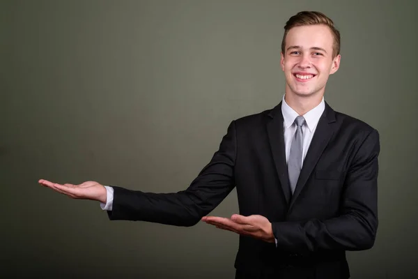 Junger gutaussehender Geschäftsmann trägt Anzug gegen farbigen Hintergrund — Stockfoto