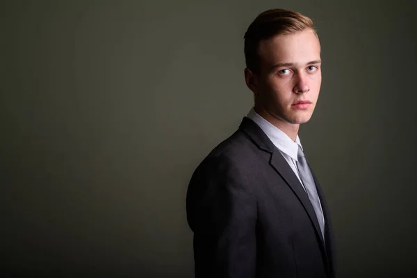 Young handsome businessman wearing suit against colored backgrou — Stock Photo, Image