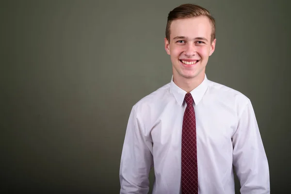 Junger gutaussehender Geschäftsmann mit blonden Haaren gegen farbigen Hintern — Stockfoto